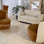 Sala moderna con sofá minimalista de 2 puestos color beige y sillas Ágata en poliuretano blanco, ubicada en showroom Innovarte. Estilo minimalista calido. Warm minimalist