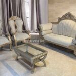 Sala clásica Isabelina Enford con un elegante terminado en poliuretano color champaña y tapizado en tela velvet beige. Compuesta por un sofá con detalles tallados a mano y dos sillas de respaldo alto, complementada con una mesa de centro en madera con cubierta de vidrio, perfecta para un ambiente sofisticado y atemporal.