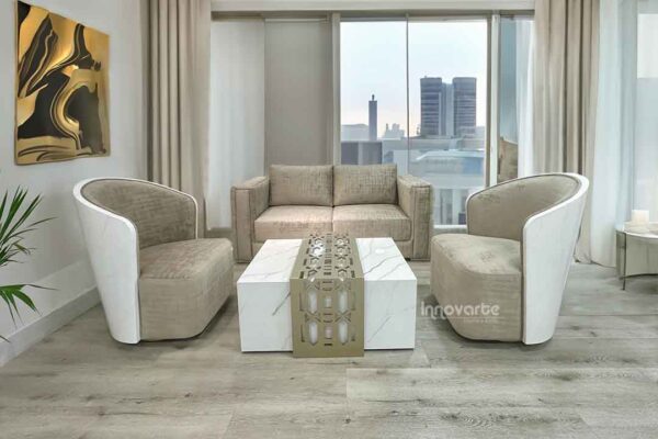 Sala moderna con sofá Golden beige y dos sillas Holandesas giratorias en tapizado claro, mesa central con terminado marmolizado blanco y detalles en madera calada pintado en poliuretano champaña.