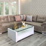 Sofá modular en forma de L tapizado en tela beige, ideal para espacios modernos y versátiles