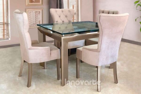 Comedor con cubierta en vidrio y sillas tapizadas en beige y pintadas en poliuretano champaña