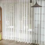 Cortina onda serena en tela translúcida blanca, creando suaves pliegues ondulados que aportan elegancia y luminosidad a la habitación