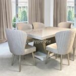 Comedor con mesa marmolizada y sillas tapizadas en beige y pintadas en poliuretano champaña