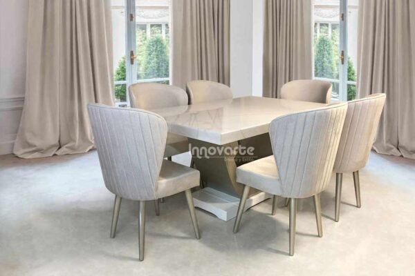 Comedor con mesa marmolizada y sillas tapizadas en beige y pintadas en poliuretano champaña