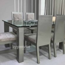 Comedor con cubierta en vidrio y sillas tapizadas en gris y pintadas en poliester ambar