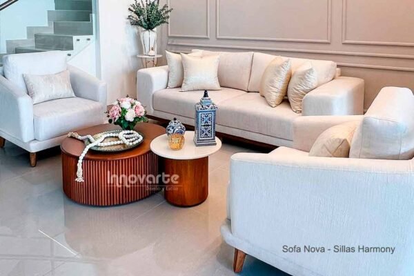 Sala moderna con sofá tapizado en tela beige y dos sillas en el mismo color, decorada con un juego de mesas de centro de madera natural y pintura color almendra con base alistonada
