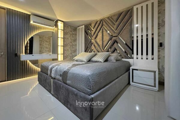 Alcoba moderna con cama tapizada y cabecero alto combinando espejos, tapizado y madera en poliuretano, destacando un diseño lujoso y elegante