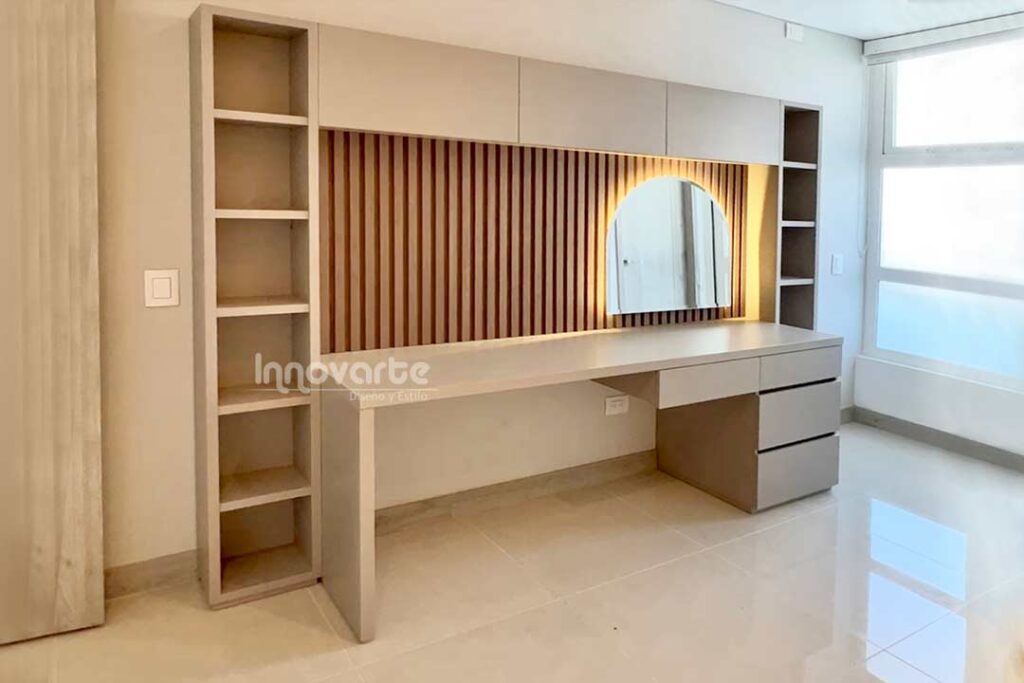 Mueble tocador/escritorio para adolescente, con espejo con luces indirectas, y cajones para maquillaje y estanterías decorativas. Fondo con pared alistonada.