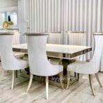 Comedor con mesa de madera marmolizada y sillas tapizadas en beige y pintadas en poliuretano