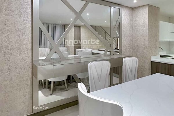 Espejo decorativo con marco champaña colgado en un comedor elegante con mesa de madera y sillas tapizadas en beige