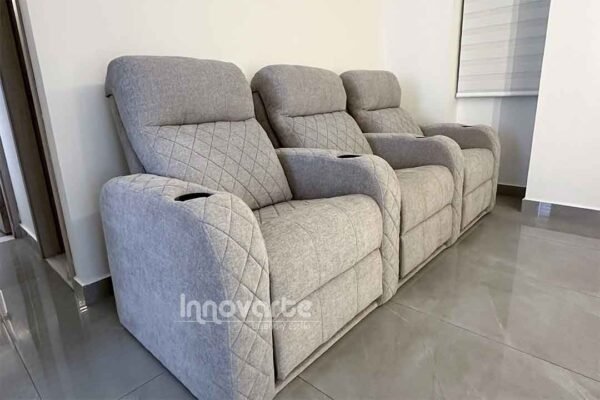 Sala de estar con sofá reclinable gris y portavasos en cada brazo