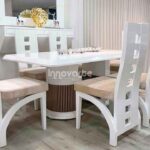 Comedor Tower de 6 puestos con mesa de base cilíndrica y cubierta blanca brillante, acompañado de asientos stairs ergonómicos en madera con diseño geométrico y asiento acolchonado. Estilo moderno y elegante para comedores sofisticados