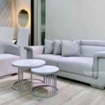 Sala moderna compuesta por sofá amplio de diseño contemporáneo en tono claro y sillas giratorias con detalle decorativo en madera calada con acabado brillante, ideal para espacios elegantes y modernos.