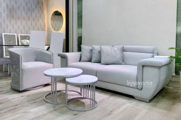 Sala moderna compuesta por sofá amplio de diseño contemporáneo en tono claro y sillas giratorias con detalle decorativo en madera calada con acabado brillante, ideal para espacios elegantes y modernos.