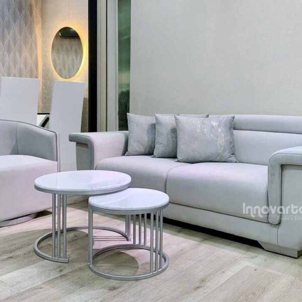 Sala moderna compuesta por sofá amplio de diseño contemporáneo en tono claro y sillas giratorias con detalle decorativo en madera calada con acabado brillante, ideal para espacios elegantes y modernos.