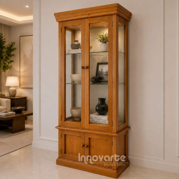 Vitrina clásica de madera maciza color miel con dos puertas de vidrio, estantes internos y gabinete inferior para almacenamiento, ubicada en una elegante sala de estilo contemporáneo.